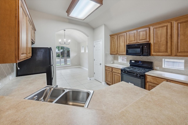 kitchen with sink, tasteful backsplash, vaulted ceiling, light tile patterned flooring, and black appliances