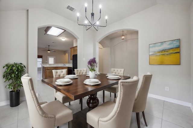 dining area with light tile patterned floors, ceiling fan with notable chandelier, lofted ceiling, and sink