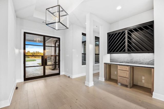 interior space featuring a notable chandelier, light wood-type flooring, and built in desk