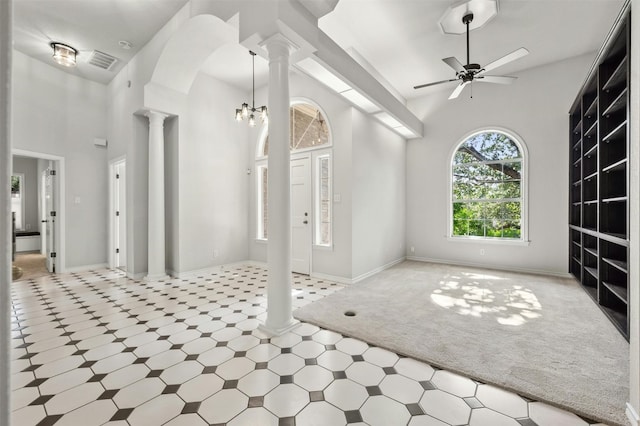 living room featuring light carpet, ornate columns, a high ceiling, and ceiling fan with notable chandelier