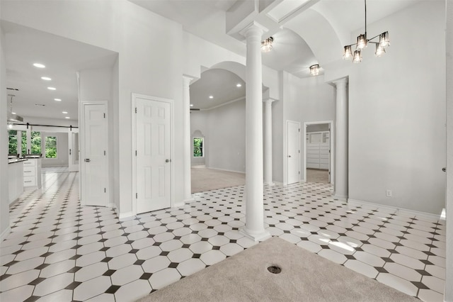 interior space with ornate columns, a towering ceiling, and tile patterned flooring