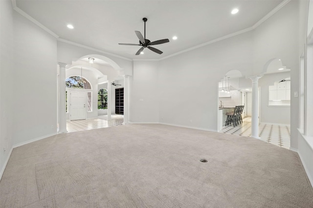 unfurnished living room featuring light carpet, decorative columns, ornamental molding, and ceiling fan