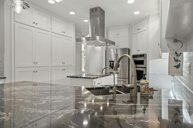 kitchen featuring island exhaust hood, white cabinets, double oven, and dark stone counters