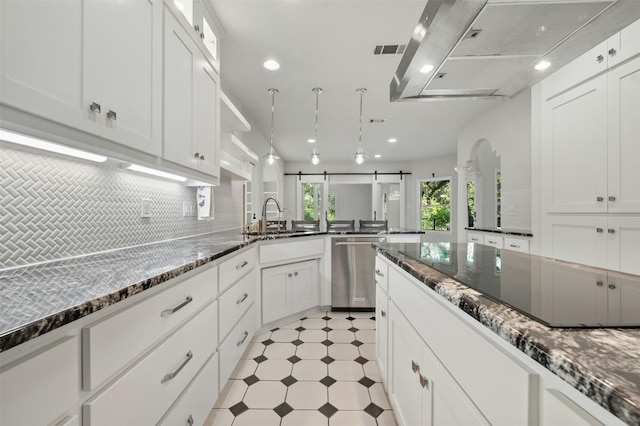 kitchen with dark stone countertops, sink, a barn door, stainless steel dishwasher, and white cabinetry