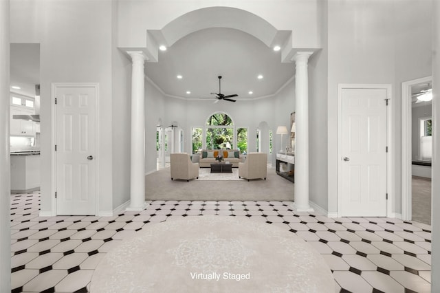 foyer with a high ceiling, ornate columns, and crown molding