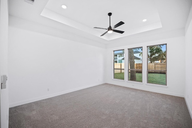 carpeted empty room featuring ceiling fan and a raised ceiling