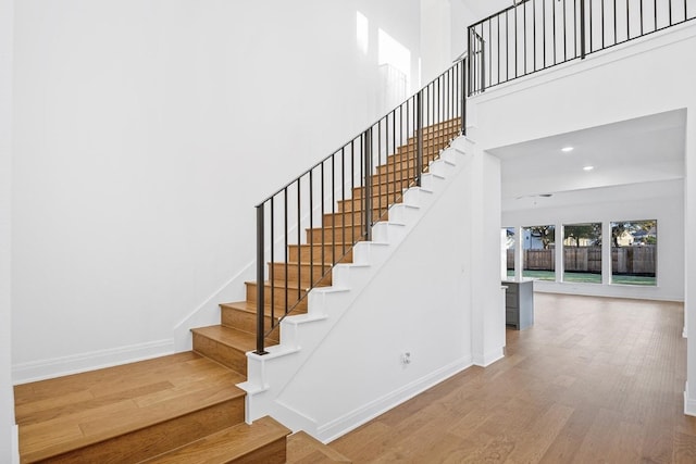 stairs featuring hardwood / wood-style flooring and a high ceiling