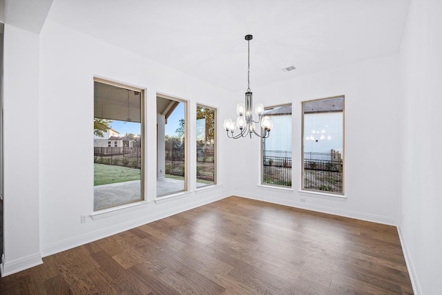 unfurnished dining area with wood-type flooring and an inviting chandelier