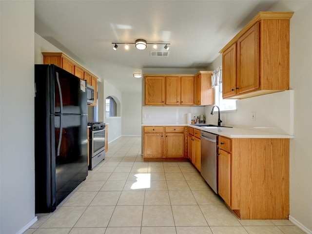 kitchen featuring sink, stainless steel appliances, light tile patterned floors, and rail lighting