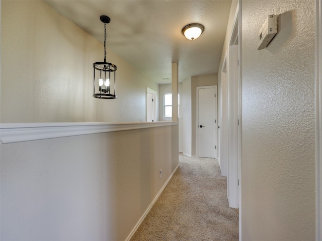 hallway with an inviting chandelier and light carpet