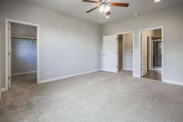 unfurnished bedroom with ceiling fan, a walk in closet, connected bathroom, and carpet floors