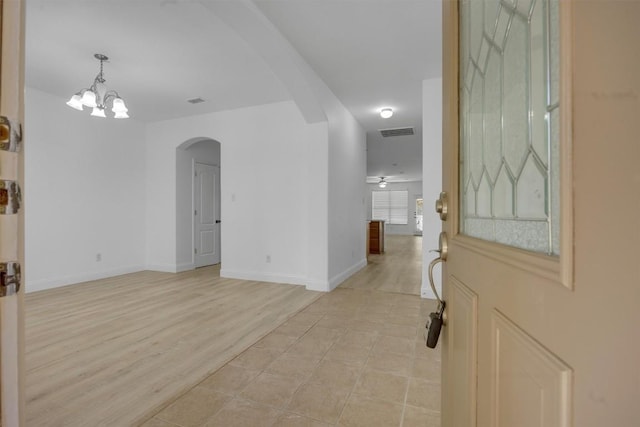 interior space with ceiling fan with notable chandelier and light wood-type flooring