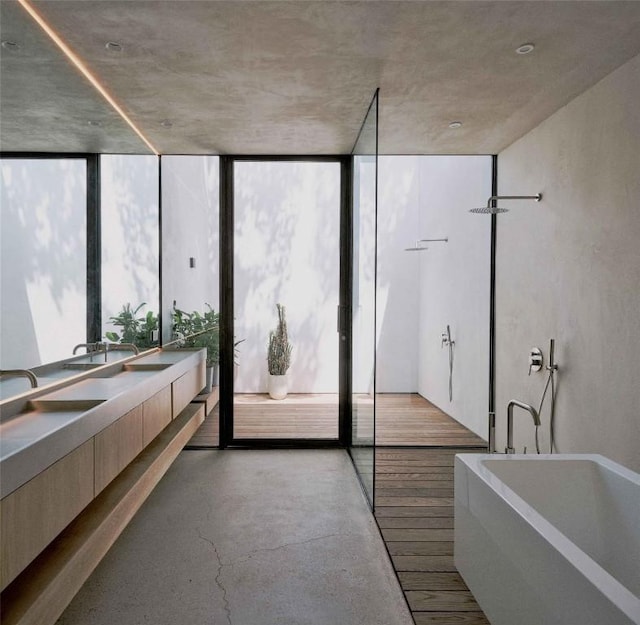 bathroom featuring floor to ceiling windows, a bathing tub, vanity, and concrete floors