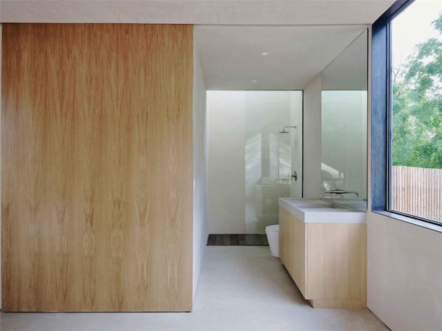 bathroom with sink, a shower, concrete floors, and toilet