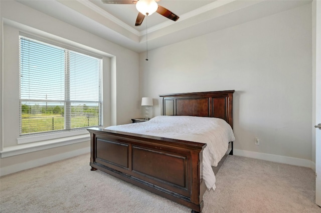 bedroom featuring ceiling fan, light carpet, and a tray ceiling