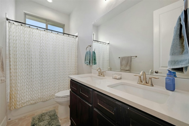 bathroom with dual vanity, toilet, and tile patterned floors