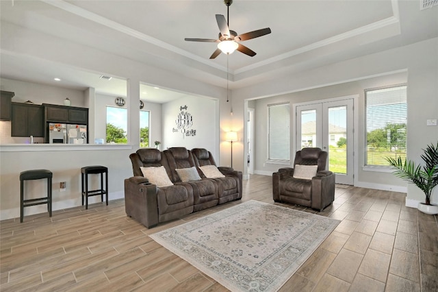 living room featuring a wealth of natural light, ceiling fan, and a raised ceiling