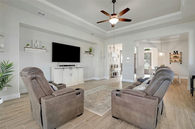 living room featuring crown molding, light wood-type flooring, ceiling fan, and a raised ceiling