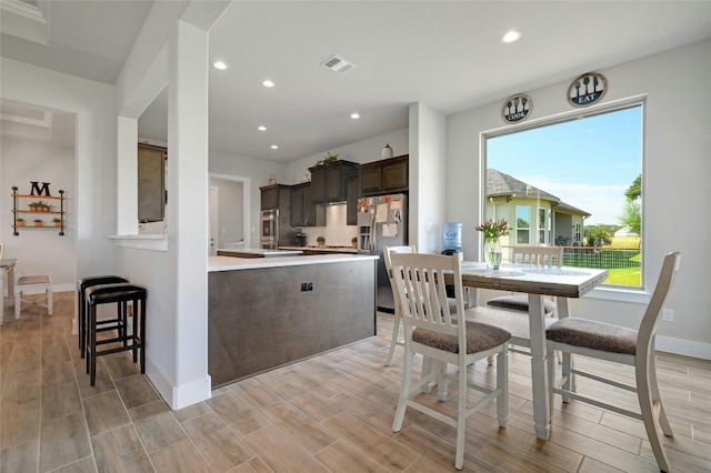 interior space with stainless steel fridge with ice dispenser, light hardwood / wood-style flooring, and dark brown cabinets