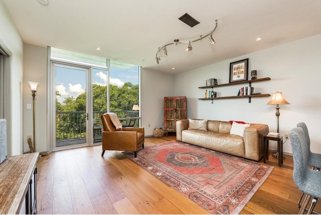 living room with floor to ceiling windows, track lighting, and light hardwood / wood-style flooring