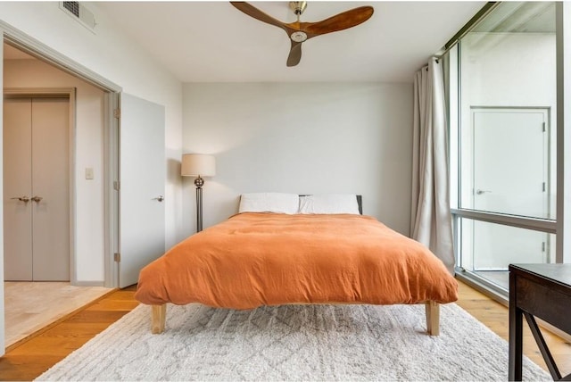 bedroom with multiple windows, ceiling fan, and light wood-type flooring