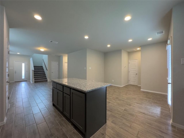 kitchen with light stone counters, recessed lighting, wood tiled floor, open floor plan, and a kitchen island