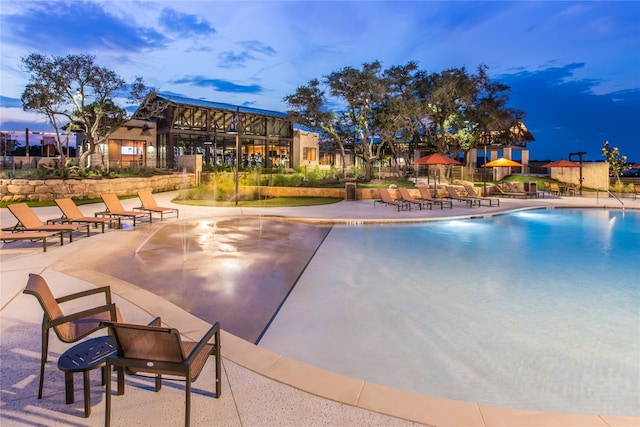 pool at dusk featuring a patio area