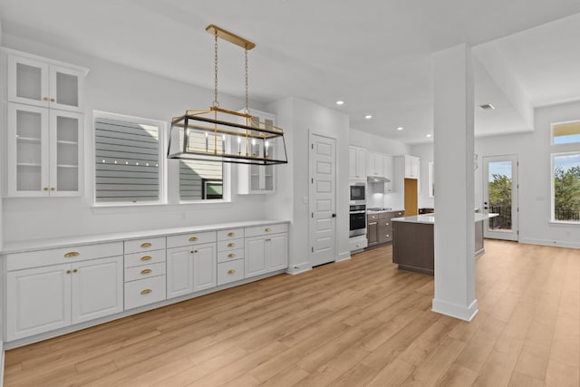 kitchen featuring a notable chandelier, white cabinets, light hardwood / wood-style flooring, decorative light fixtures, and stainless steel appliances