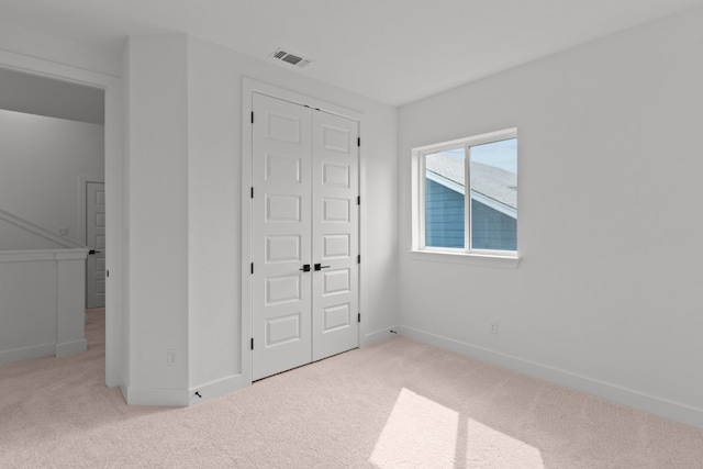 unfurnished bedroom featuring light carpet and a closet