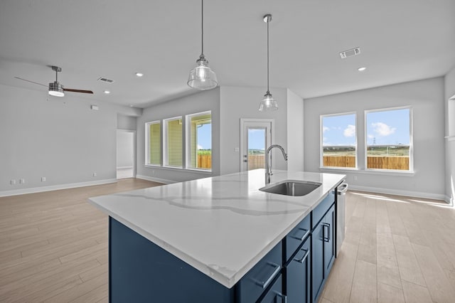 kitchen with a center island with sink, sink, pendant lighting, and blue cabinets