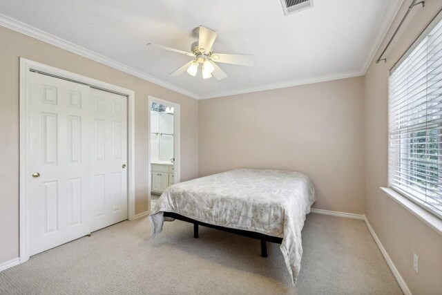 carpeted bedroom with a closet, ceiling fan, and crown molding