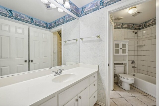 full bathroom featuring tiled shower / bath combo, vanity, tile patterned flooring, and toilet