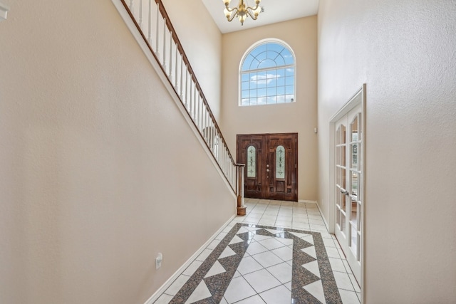 tiled entrance foyer with a chandelier, french doors, and a towering ceiling