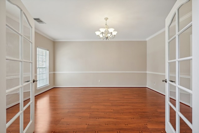 empty room featuring hardwood / wood-style flooring, french doors, and a chandelier