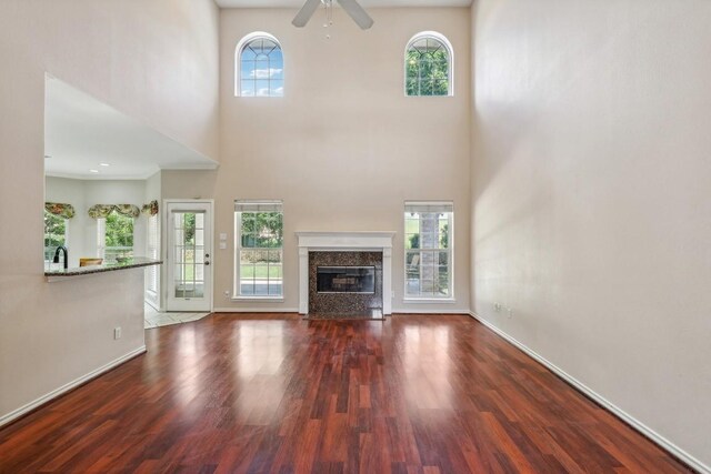 unfurnished living room with hardwood / wood-style flooring, a high end fireplace, and ceiling fan