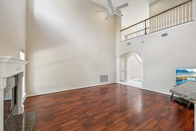 unfurnished living room featuring a high ceiling, a fireplace, ceiling fan, and hardwood / wood-style floors