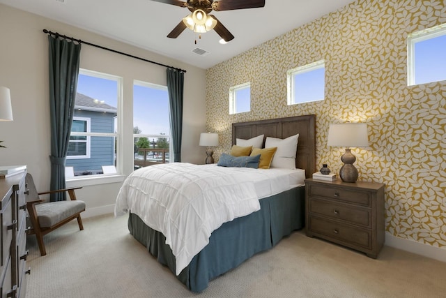 bedroom featuring light carpet, ceiling fan, and multiple windows