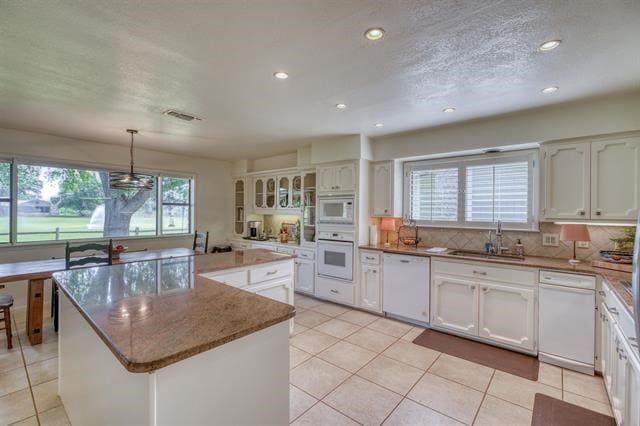 kitchen featuring sink, light tile patterned flooring, a kitchen island, and white appliances