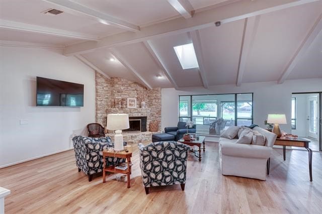 living room featuring a fireplace, lofted ceiling with skylight, and light hardwood / wood-style flooring