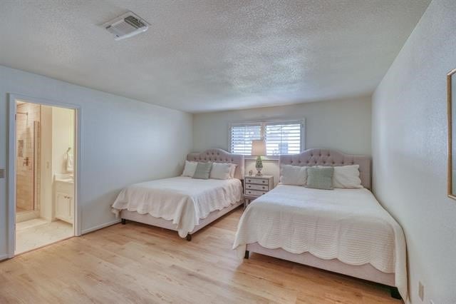 bedroom featuring ensuite bathroom, a textured ceiling, and hardwood / wood-style floors