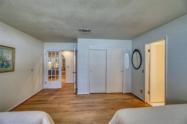 bedroom featuring light hardwood / wood-style floors, a closet, and a textured ceiling