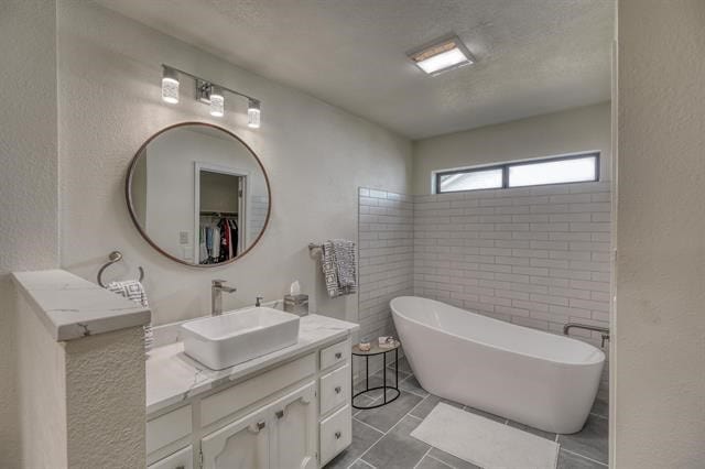 bathroom featuring vanity, a washtub, and tile patterned floors