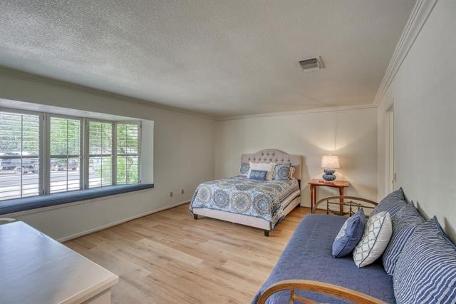 bedroom featuring ornamental molding, a textured ceiling, and light wood-type flooring