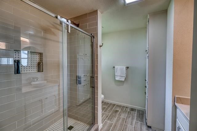 bathroom with a shower with door, vanity, and toilet