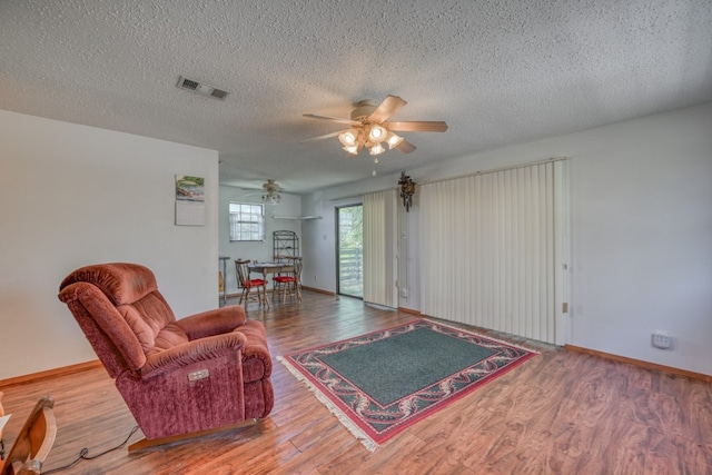 living room with ceiling fan, wood-type flooring, and a textured ceiling