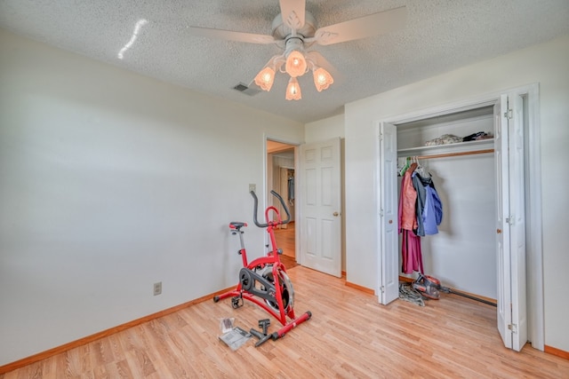 bedroom featuring a textured ceiling, a closet, light wood-type flooring, and ceiling fan