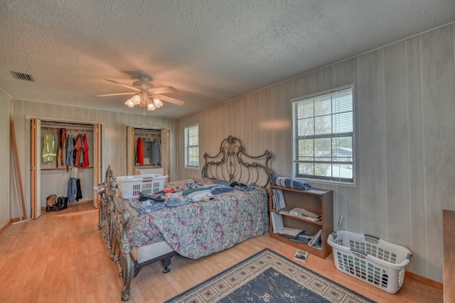 bedroom featuring multiple windows, light wood-type flooring, ceiling fan, and a textured ceiling