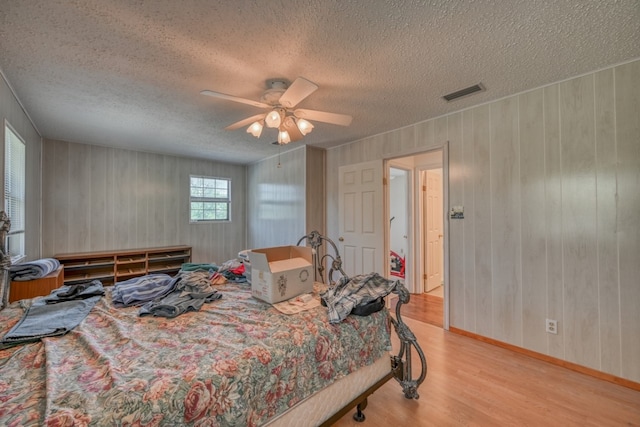 bedroom with light hardwood / wood-style flooring, a textured ceiling, and ceiling fan