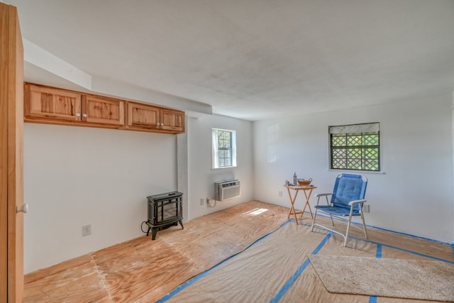 living area with an AC wall unit, light hardwood / wood-style flooring, and a wood stove