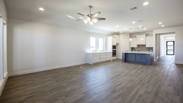 kitchen featuring an island with sink, white cabinets, ceiling fan, and dark hardwood / wood-style floors